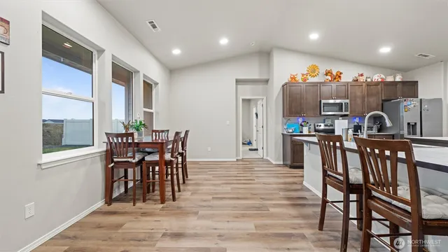 a kitchen with stainless steel appliances kitchen island granite countertop a table chairs sink and cabinets