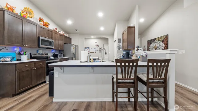 a kitchen with stainless steel appliances granite countertop a kitchen island a chairs a sink and a refrigerator