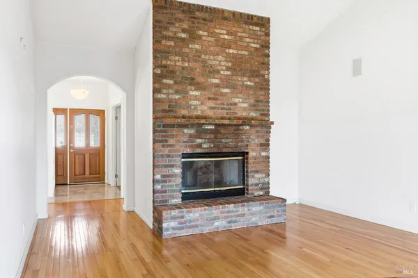 an empty room with wooden floor fireplace and windows