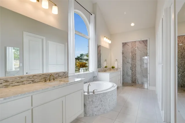 a bathroom with a granite countertop sink a mirror a bathtub and shower