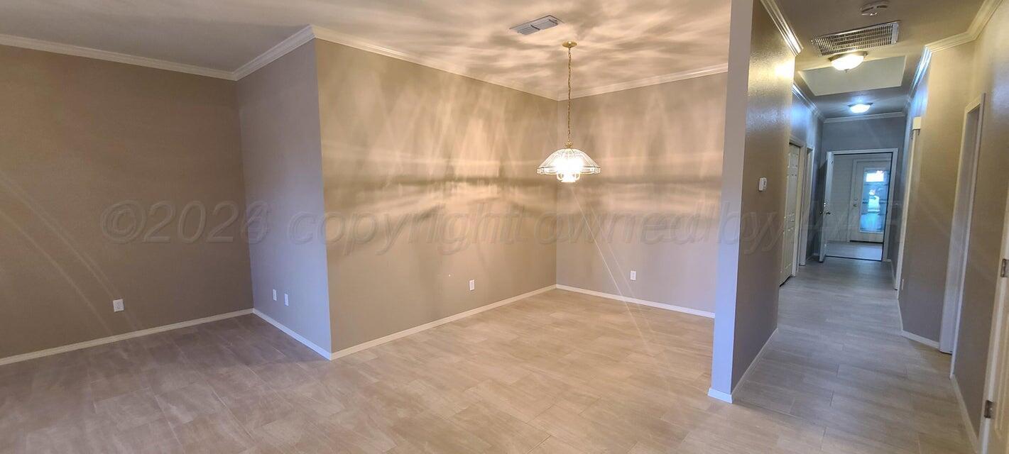 3531 West Point Drive Amarillo, TX 79119 - Photo 4 of 12 an empty room with kitchen view and a chandelier fan