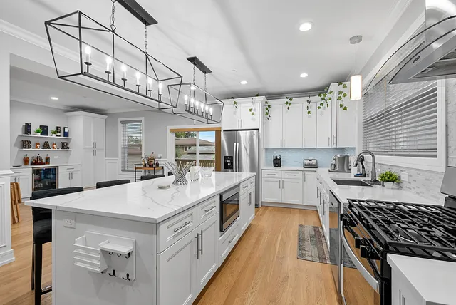 a large white kitchen with lots of counter space wooden floor and stainless steel appliances