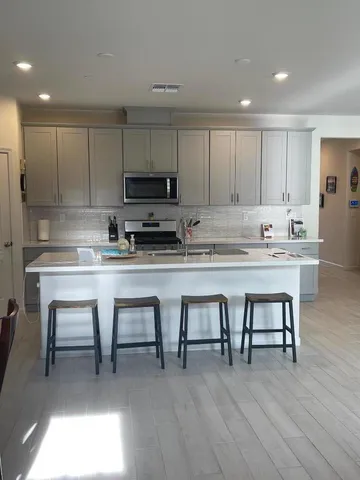 a kitchen with stainless steel appliances granite countertop a table chairs sink microwave and cabinets
