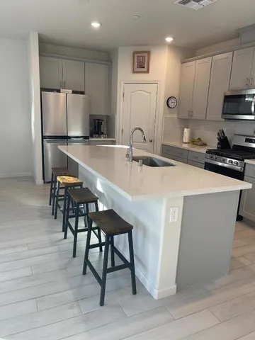 a kitchen with stainless steel appliances granite countertop a table chairs sink and cabinets
