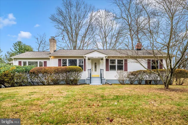 a front view of a house with a yard covered with trees