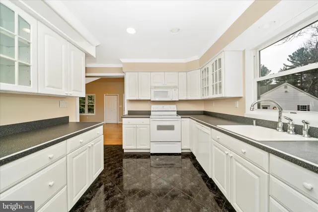 a kitchen with granite countertop white cabinets and white appliances