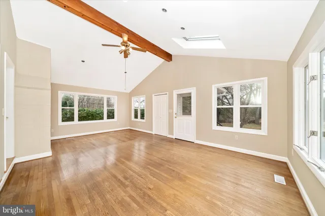 a view of an empty room with a window and wooden floor