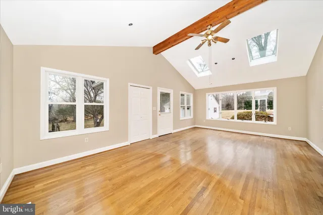 a view of an empty room with a window and wooden floor