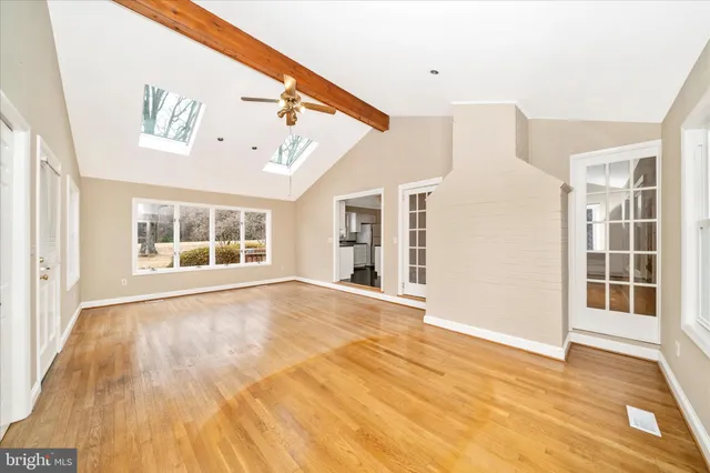 a view of an empty room with wooden floor and windows