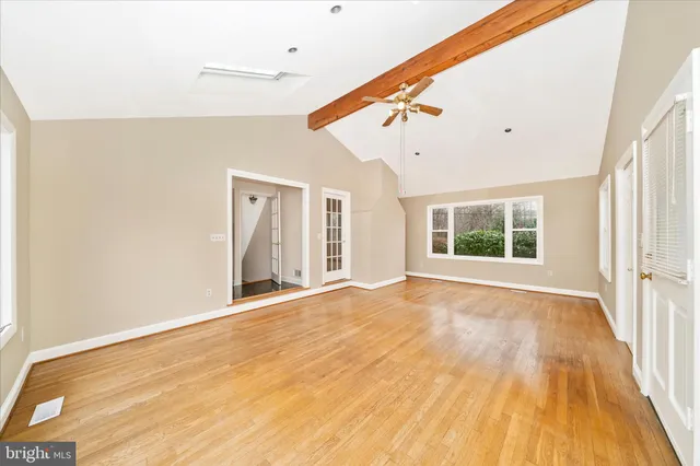 a view of an empty room with wooden floor and a window