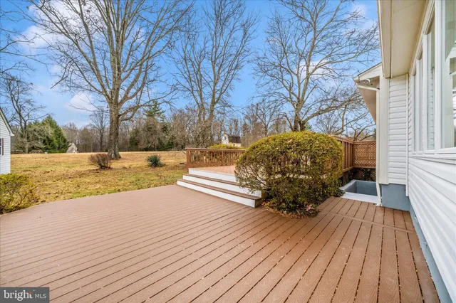 a view of a white house next to a road with large trees