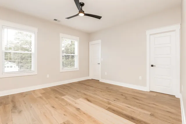 a view of empty room with wooden floor and fan