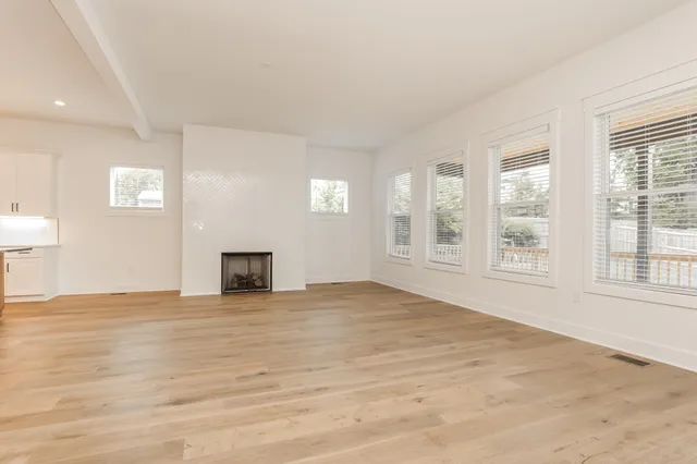 a view of an empty room with a window and fireplace