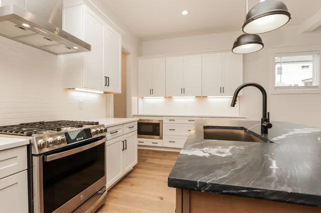 a kitchen with kitchen island stainless steel appliances a sink a stove and a counter space