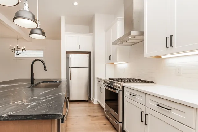 a kitchen with kitchen island stainless steel appliances granite countertop a stove a sink and a refrigerator