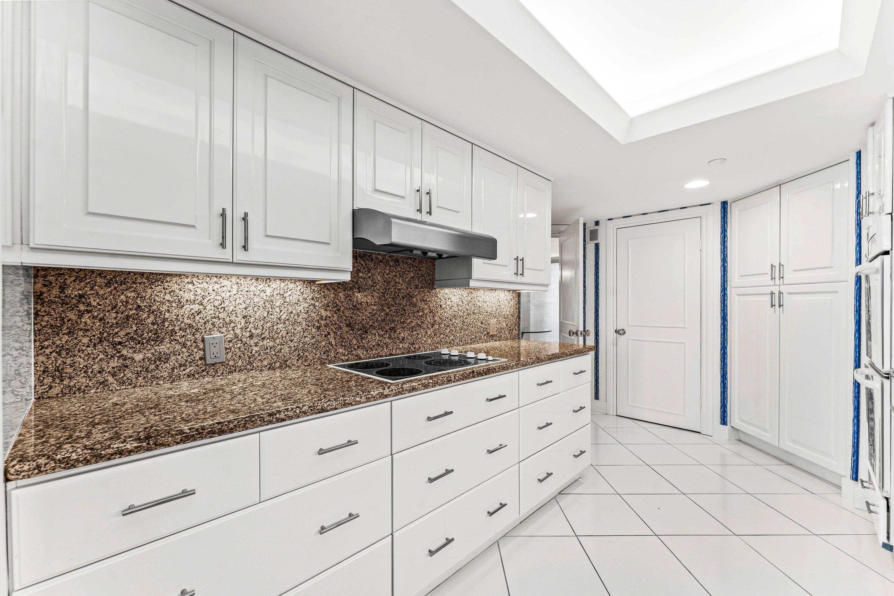 3170 South Ocean Boulevard, Unit S302 Palm Beach, FL 33480 - Photo 8 of 34 a kitchen with granite countertop white cabinets and stainless steel appliances