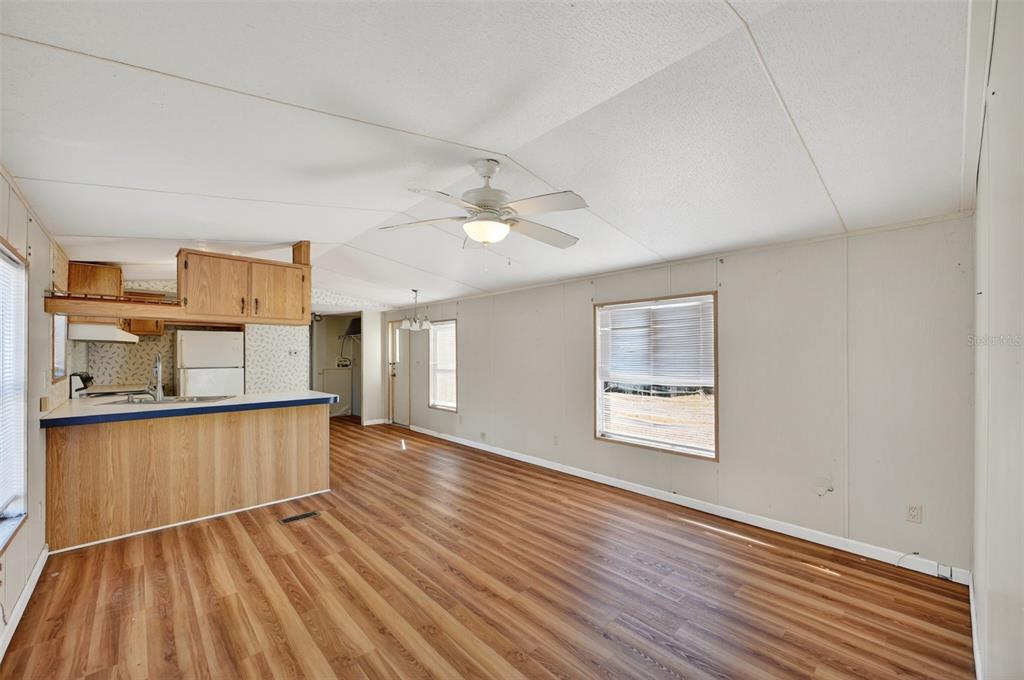 7405 Bonnie Lake Road Brooksville, FL 34601 - Photo 4 of 14 an empty room with wooden floor kitchen view and windows