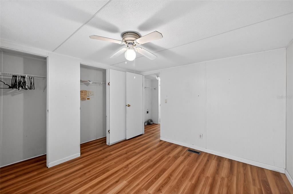 7405 Bonnie Lake Road Brooksville, FL 34601 - Photo 7 of 14 an empty room with wooden floor fan and windows