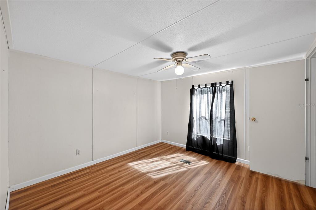7405 Bonnie Lake Road Brooksville, FL 34601 - Photo 9 of 14 a view of empty room with wooden floor and fan