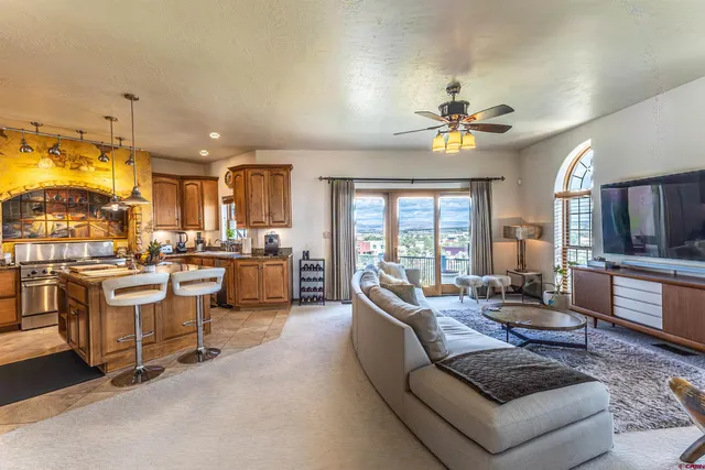 a living room with furniture kitchen view and a large window