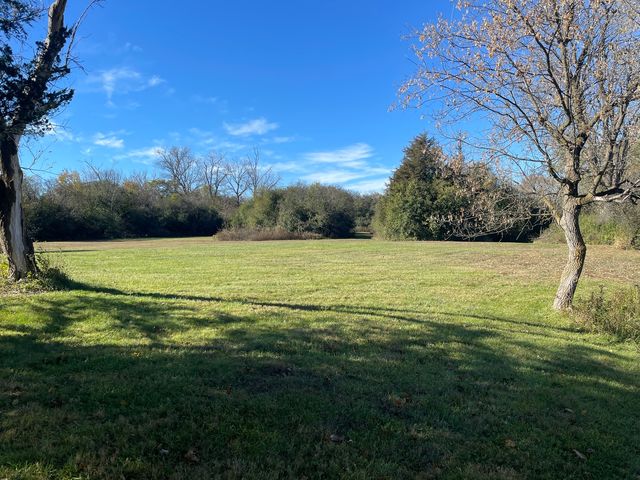a view of a field with an trees in the background