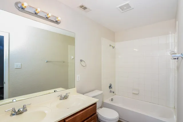 a bathroom with a bathtub shower sink mirror and toilet