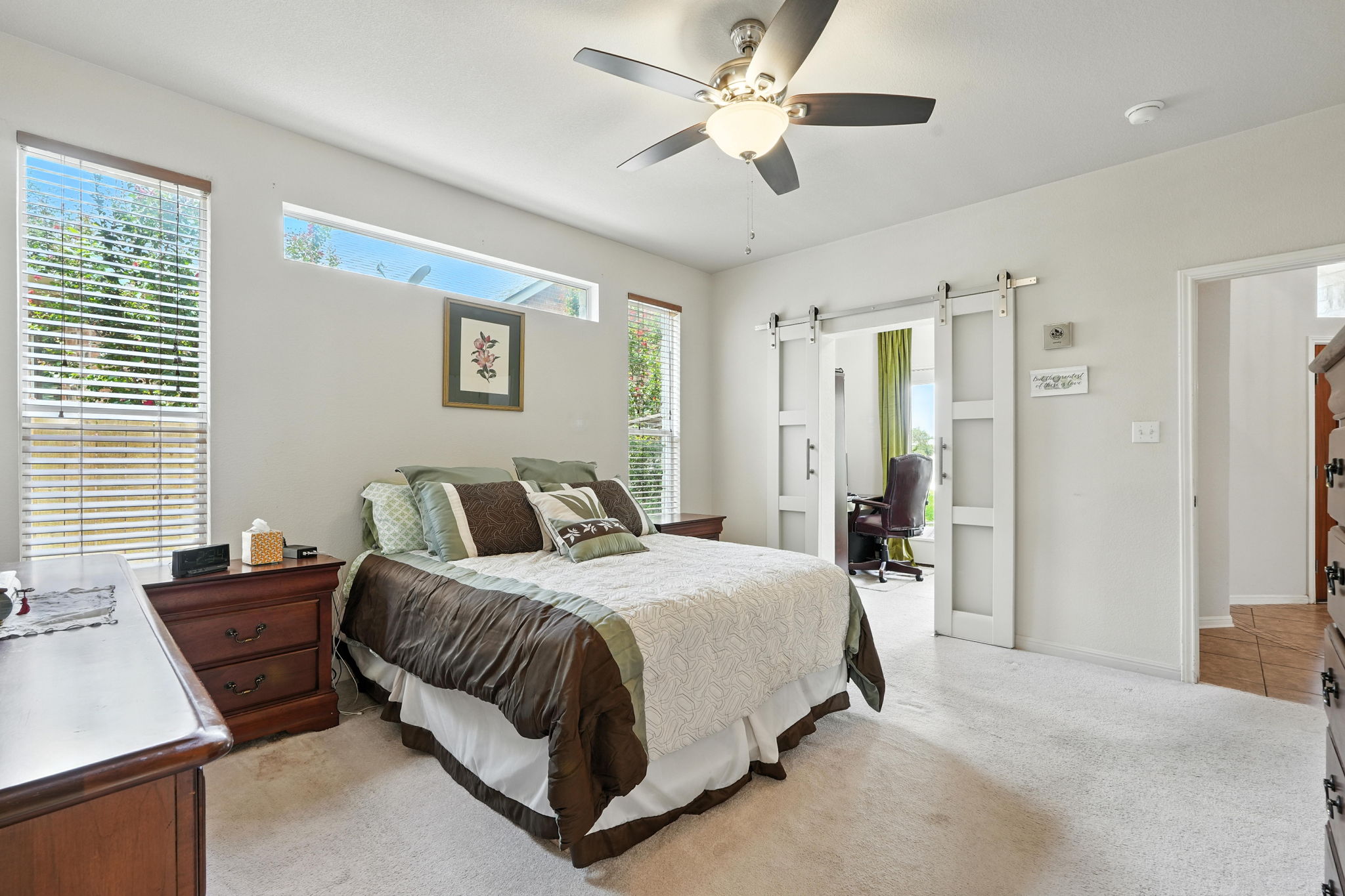 1802 Misty Ridge Leander, TX 78641 - Photo 16 of 39 Primary Bedroom featuring a desk, light colored carpet, a barn door, and a ceiling fan
