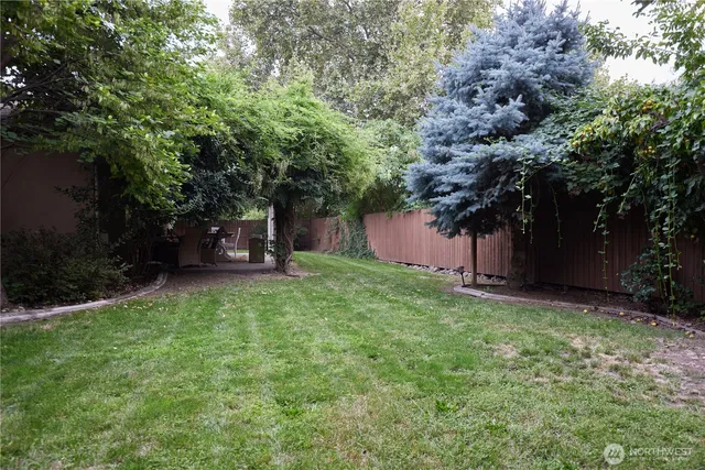 a view of a house with backyard and wooden fence