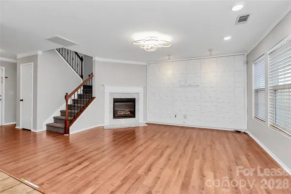 a view of an empty room with wooden floor fireplace and a window