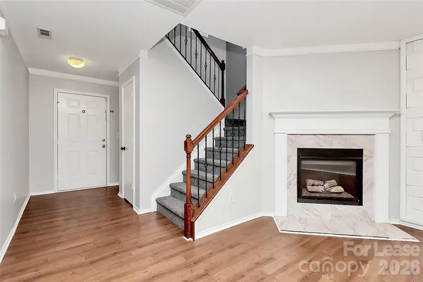 a view of an empty room with wooden floor and a fireplace