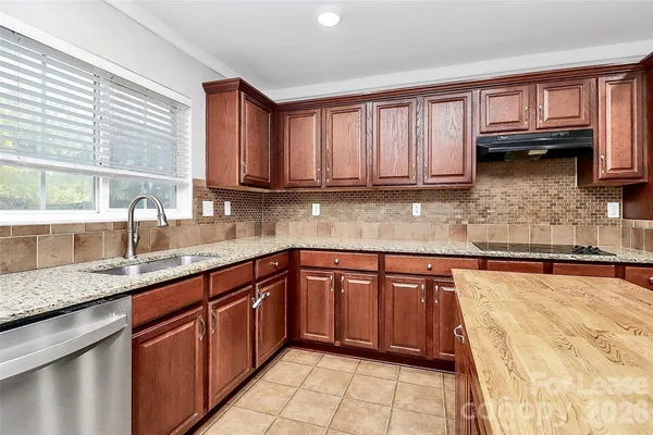 a kitchen with stainless steel appliances granite countertop a sink dishwasher stove and cabinets with wooden floor