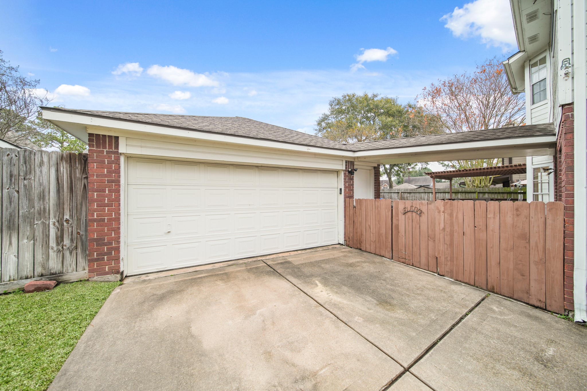 16114 Kintyre Point Road Houston, TX 77095 - Photo 5 of 44 This photo shows a spacious driveway with a double garage featuring a white door. It has a wooden fence and brick accents, creating a welcoming entryway to the home.