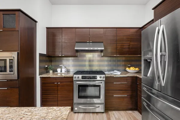 a kitchen with stainless steel appliances granite countertop a refrigerator a stove and a sink