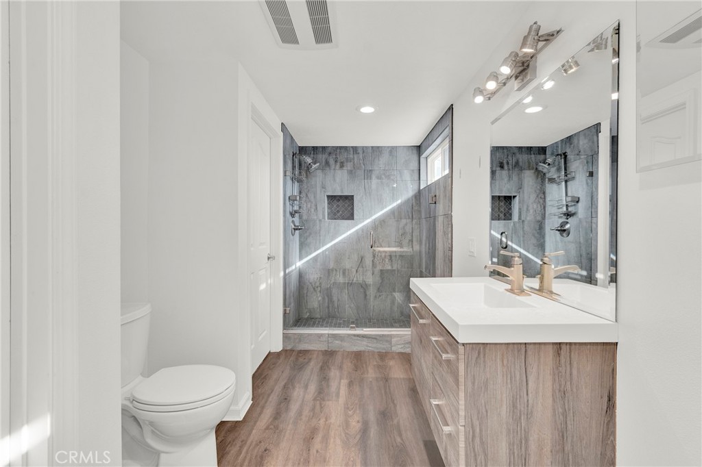 13381 Epping Way Tustin, CA 92780 - Photo 31 of 52 a bathroom with a sink a toilet a mirror and vanity