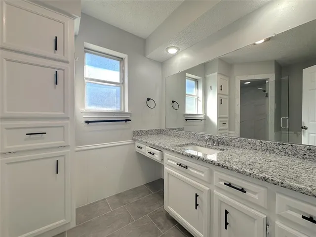 a bathroom with a granite countertop toilet a sink and a shower