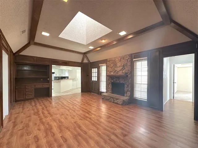 an empty room with wooden floor and fireplace