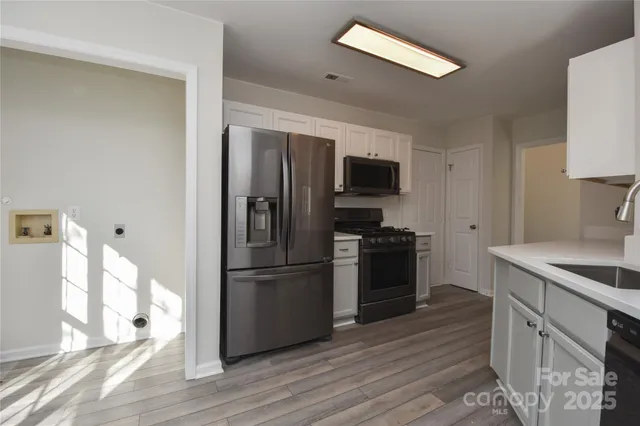 a kitchen with a refrigerator stove and wooden floor