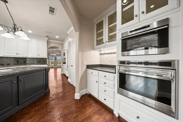a large kitchen with cabinets wooden floor and stainless steel appliances