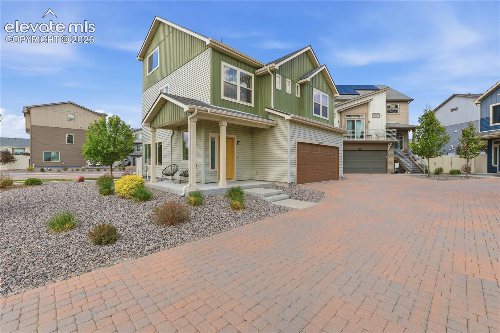6008 Ashmore Road Colorado Springs, CO 80927 - Photo 4 of 48 Modern two-story residence featuring a covered porch with column supports, a prominent yellow front door, and a brown garage door