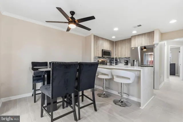 a kitchen with stainless steel appliances kitchen island granite countertop a dining table chairs and a refrigerator