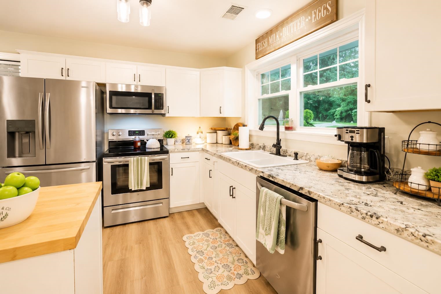 10093 Mt Carmel Road Brighton, TN 38011 - Photo 19 of 36 Bright kitchen featuring white cabinetry, stainless steel appliances, light-toned wood-finish flooring, and a window above the sink