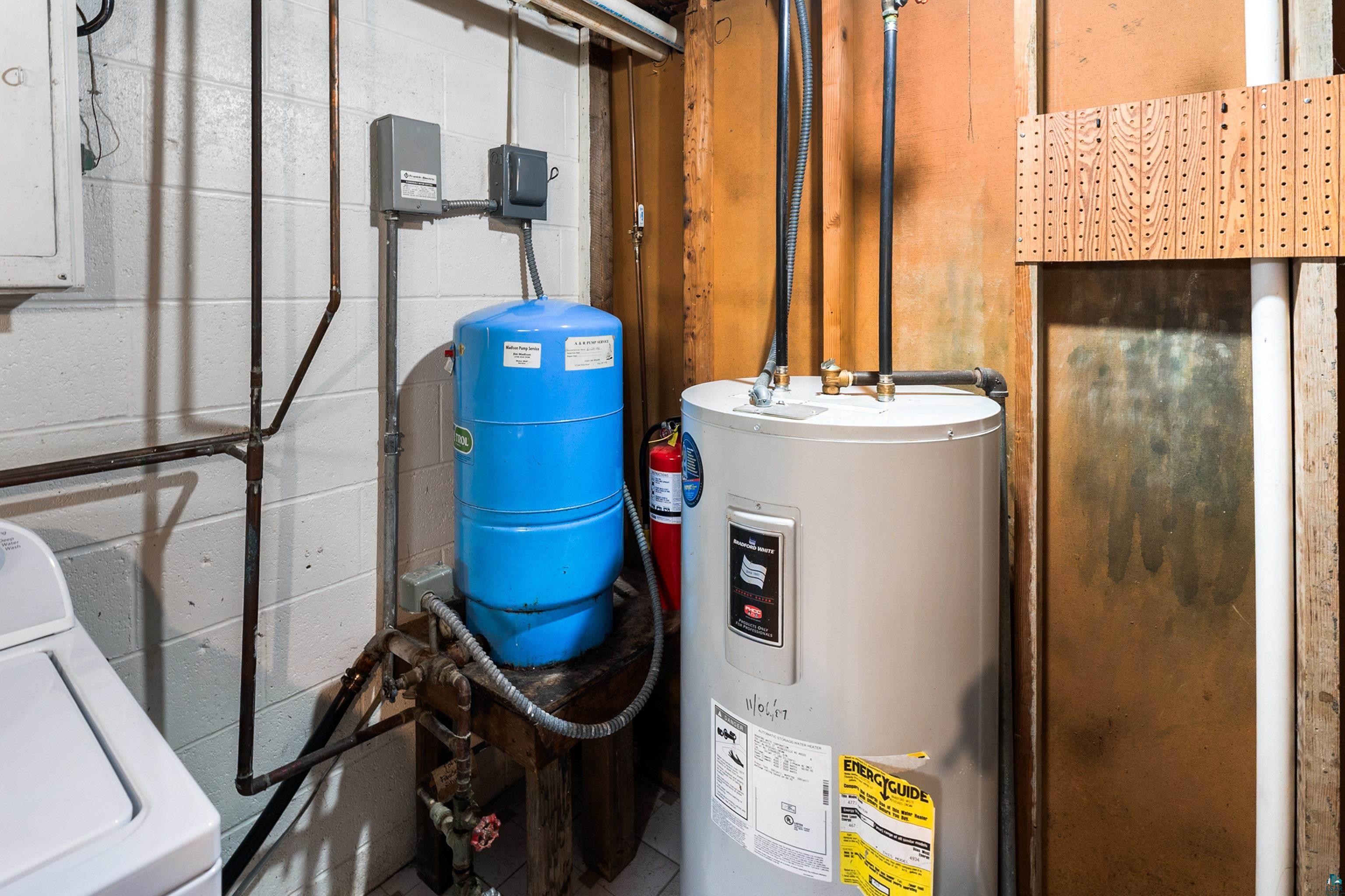 4808 Midway Road Duluth, MN 55811 - Photo 44 of 57 Utility area featuring a water heater, blue pressure tank, and exposed plumbing