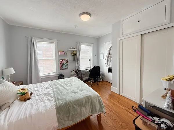 a bedroom with a bed a table and wooden floor