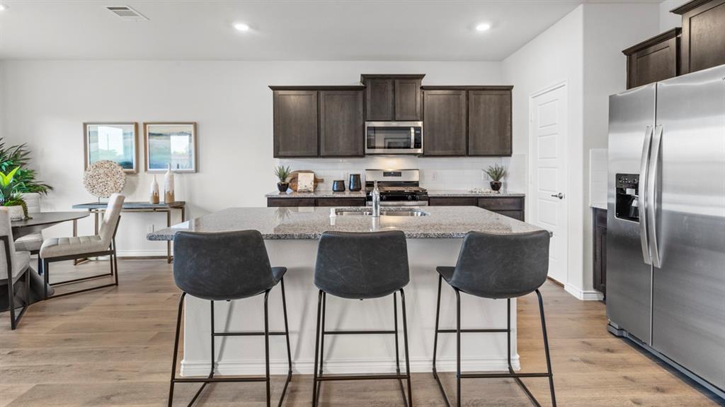 500 Range Road Caddo Mills, TX 75135 - Photo 28 of 35 Open-concept kitchen featuring a spacious island with granite countertop, dark wood-finish cabinetry, stainless steel appliances, and wood-finish flooring
