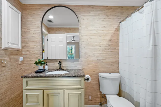 a bathroom with a granite countertop toilet a sink and a mirror