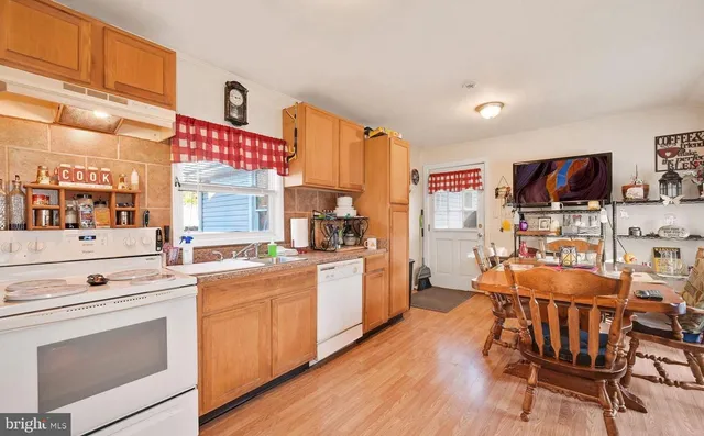 a kitchen with stainless steel appliances a stove a sink dishwasher and a refrigerator with wooden floor