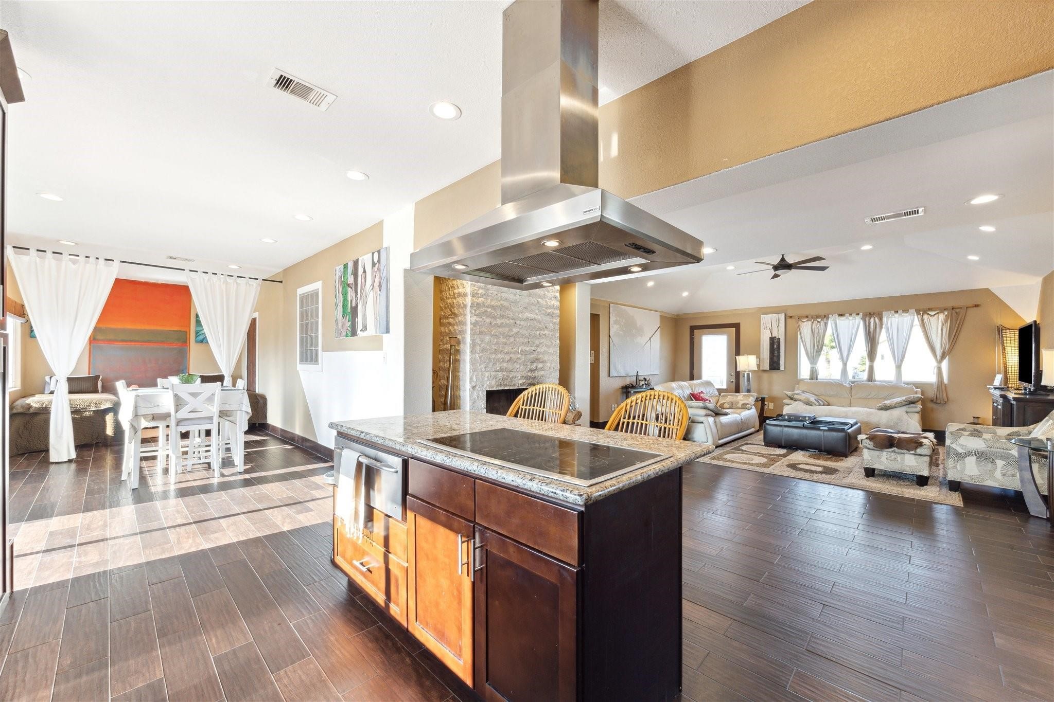 410 Isles End Road Tiki Island, TX 77554 - Photo 4 of 13 This open-concept living space features a modern kitchen island with granite countertops, overlooking a spacious living room with ample natural light. The dining area is set off to the side, creating a seamless flow perfect for entertaining. Rich wood tile flooring adds warmth throughout.