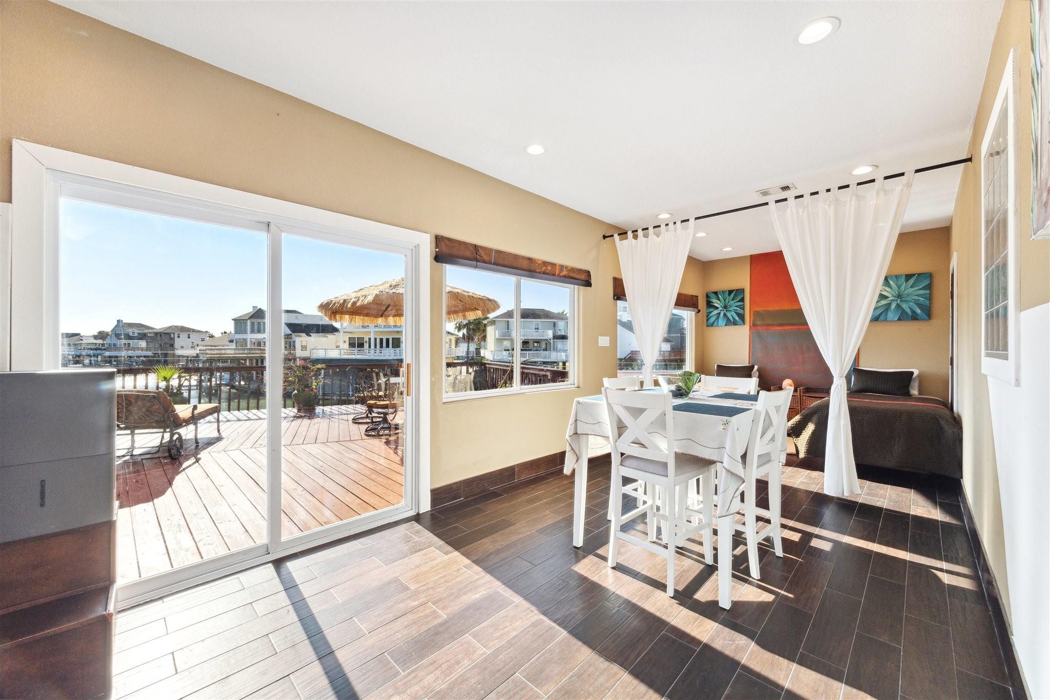 410 Isles End Road Tiki Island, TX 77554 - Photo 6 of 13 This photo showcases a bright, open-concept living space with large sliding glass doors leading to a waterfront deck. Perfect for enjoying indoor-outdoor living.