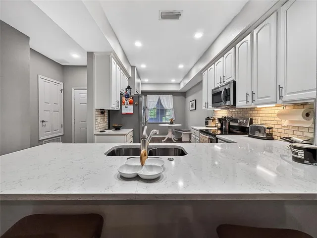 a kitchen with kitchen island a stove top oven a sink a counter top space and cabinets