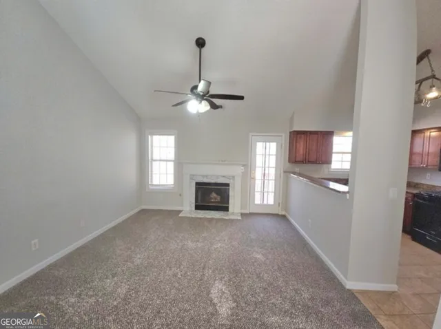 a view of a livingroom with a fireplace a ceiling fan and windows
